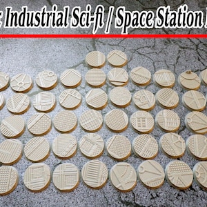 May include: 10x Industrial Sci-fi / Space Station Bases. A set of 10x 1-inch round plastic bases with various industrial and sci-fi designs. The bases are beige in color and have a textured surface.