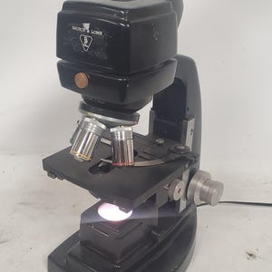 Microscopio de laboratorio monocular de campo plano Bausch & Lomb antiguo con 3 objetivos.