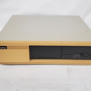 May include: A vintage Mitac desktop computer case with a beige top panel and a yellowed front bezel. The front features a black panel with a horizontal floppy disk drive slot on the right side and the Mitac logo printed on the left side.