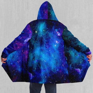 May include: A hooded cloak with a galaxy print featuring blue, purple, and black colors. The cloak has a long, flowing design and a hood that can be pulled up over the head.