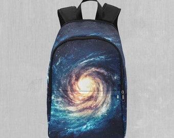 Puede incluir: Una mochila negra con cierre de cremallera. La mochila presenta un diseño de galaxia giratoria en tonos azules, amarillos y blancos.