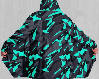 Peut inclure: Une cape à capuche avec un motif de camouflage abstrait noir et turquoise. La cape a une coupe longue et fluide et une capuche qui peut être tirée sur la tête.