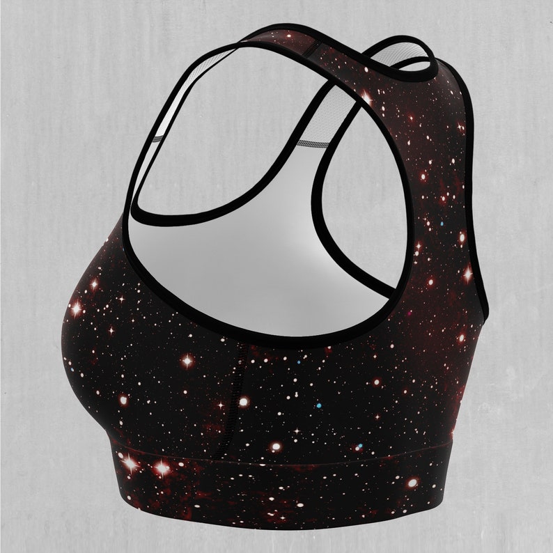 Op de afbeelding: Zwarte sportbeha met een galaxy print. De beha heeft een racerback-stijl en een mesh-paneel in de rug.