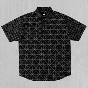 Op de afbeelding: Een zwart, kort mouwig overhemd met knopen en een wit geometrisch patroon.