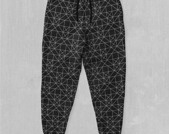 May include: Black sweatpants with a white geometric pattern. The sweatpants have a drawstring waistband.