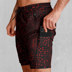 Könnte beinhalten: Schwarze Sport-Shorts mit einem roten Schaltkreis-Muster. Die Shorts haben eine Seitentasche mit einem Smartphone darin.
