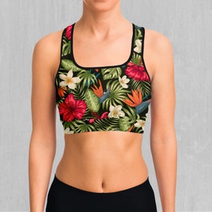 Può includere: Un reggiseno sportivo nero con stampa floreale tropicale che presenta ibisco, uccello del paradiso e altri fiori su uno sfondo verde scuro.