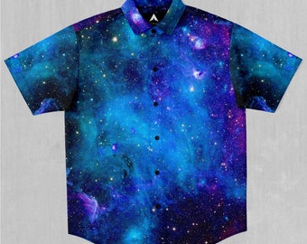 Puede incluir: Una camisa de manga corta con botones y estampado de galaxia en tonos azules, morados y negros. La camisa tiene cuello abotonado y cierre de botones.