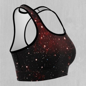 Op de afbeelding: Een zwarte sportbeha met een galaxy print met rode, witte en blauwe sterren. De beha heeft een racerback-stijl en is gemaakt van een rekbare, comfortabele stof.