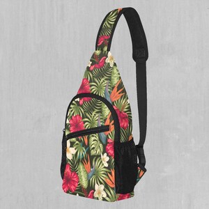 May include: A black sling bag with a tropical floral print featuring red, pink, and yellow flowers, green leaves, and orange birds. The bag has a mesh pocket on the front.