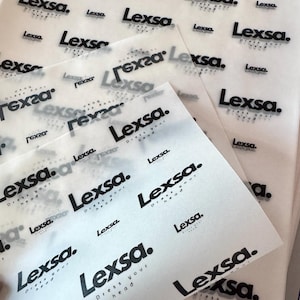May include: Close-up of several sheets of white tissue paper with the text "Lexsa. Dress your head" printed in black.