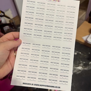 Może przedstawiać: Arkusz białych naklejek z czarnym napisem "BEST BEFORE". Każda naklejka ma linię do wpisania daty. Tekst "Restock at www.HOPPityDESIGNS.co.uk" jest wydrukowany na dole.