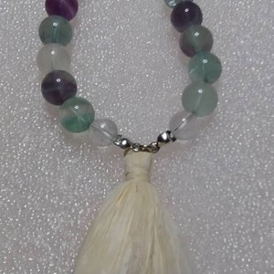 Purple, green and clear beaded bracelet with raffia tassel