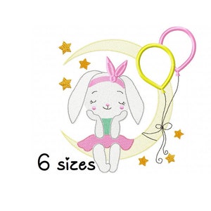 Pode incluir: Desenho bordado de um coelho branco sentado em uma lua crescente amarela com dois balões, um amarelo e outro rosa. O coelho está vestindo um vestido rosa e um laço rosa. Há estrelas douradas ao redor da lua. O texto "6 tamanhos" está abaixo da lua.