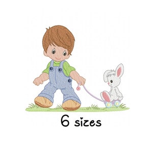 Pode incluir: Um menino com macacão azul e camisa verde caminha com um coelho branco em um carrinho de brinquedo. O coelho está usando uma coleira rosa e o carrinho tem rodas roxas. O texto "6 tamanhos" está abaixo da imagem.
