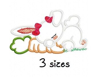 May include: An embroidered design of a sleeping white bunny with a red bow, orange paws, and a green leaf. The text "3 sizes" is below the bunny. This design is suitable for various craft projects.