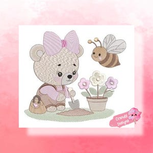 Pode incluir: Design bordado com um ursinho com laço rosa e macacão, jardinando com uma pá. Uma abelha de desenho animado paira por perto. Um vaso de flores está à direita. O design está em um fundo branco com borda rosa.