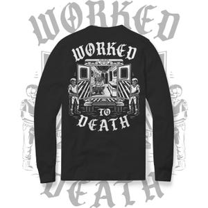May include: Black long-sleeve shirt with a graphic on the back featuring an ambulance with open doors, a skeleton patient, and two skeleton attendants. The text reads "WORKED TO DEATH" in a gothic font.