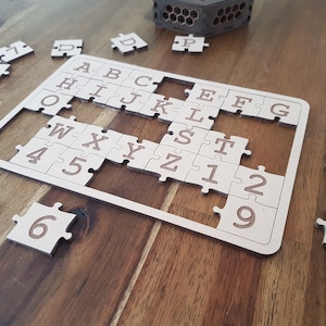 May include: A wooden alphabet and number puzzle with pieces scattered around a frame. The pieces are labeled with letters A through Z and numbers 1 through 9.