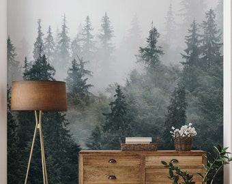 May include: A wooden dresser with six drawers and black metal handles sits in front of a wall mural depicting a misty forest with tall evergreen trees.