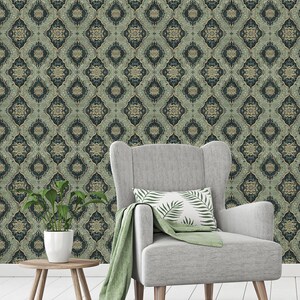 May include: A gray armchair with a green throw blanket and a pillow with a green leaf pattern sits in front of a wall covered in green and gold patterned wallpaper.