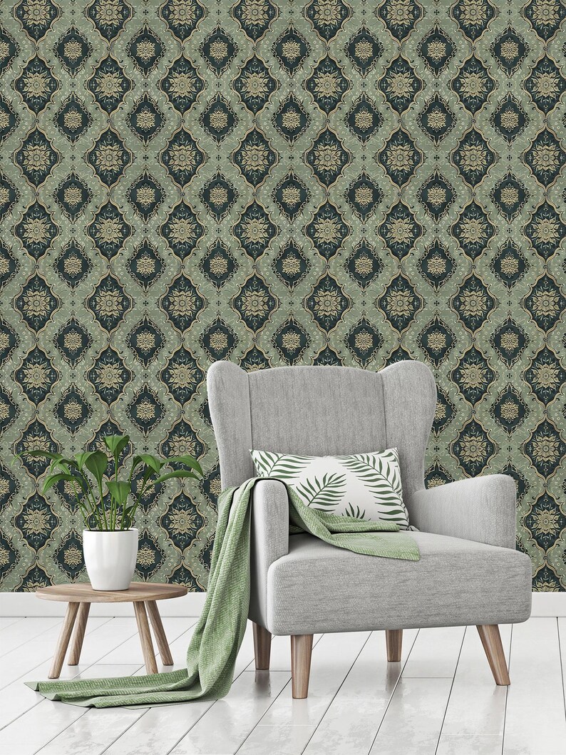 May include: A gray armchair with a green throw blanket and a pillow with a green leaf pattern sits in front of a wall covered in green and gold patterned wallpaper.
