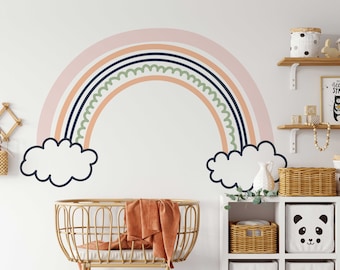 May include: A large wall decal of a rainbow in pastel colors, including pink, peach, navy, and green, with white cloud accents. The rainbow is a decorative element for a nursery or children's room.