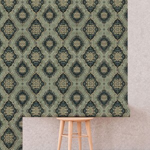 May include: A green and gold patterned wallpaper with a repeating geometric design. The wallpaper is hanging on a wall with a wooden stool in front of it.