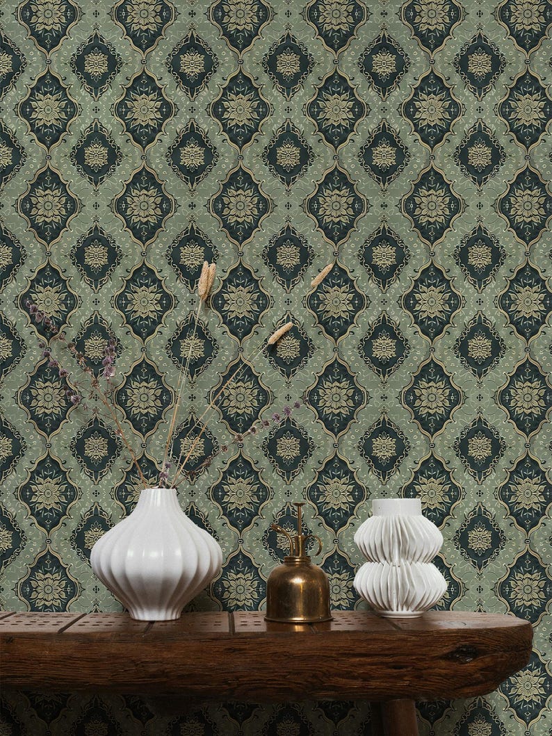 May include: A green and gold patterned wallpaper with a repeating geometric design. Two white ceramic vases and a gold metal watering can are arranged on a wooden table in front of the wallpaper.