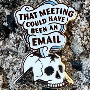 May include: A white enamel pin with a skull and a speech bubble that says "That meeting could have been an email".