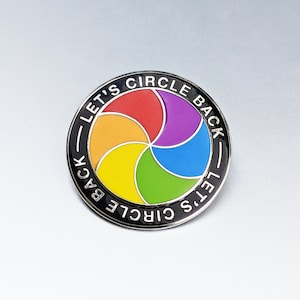 May include: A black and white enamel pin with a rainbow circle design and the text "Let's Circle Back" around the outside.