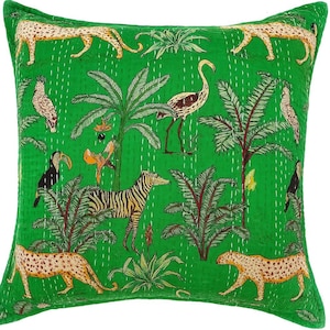 May include: A square green decorative pillow with a jungle-themed design. The pillow features illustrations of leopards, zebras, birds, and palm trees. The design is printed on a quilted fabric with white stitching.