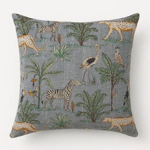 May include: Square throw pillow with a gray background featuring a jungle scene. The design includes zebras, leopards, birds, and palm trees in shades of green, tan, and black. The pillow has a quilted texture.
