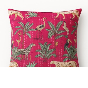 May include: A square magenta pillow with a jungle-themed print. The design features zebras, leopards, toucans, and palm trees. The pillow has a quilted texture with white stitching.