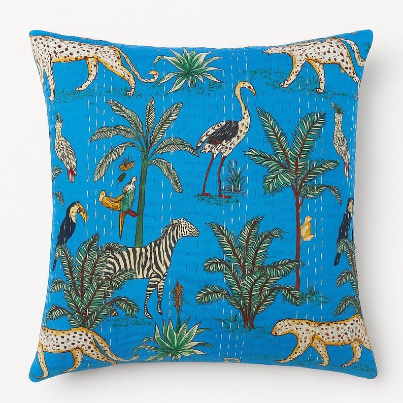 May include: Square throw pillow with a vibrant blue background featuring a jungle-themed pattern. The design includes zebras, leopards, birds, palm trees, and other tropical elements. The pillow has a stitched texture.