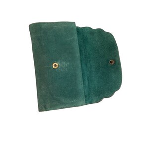 May include: A teal green suede wallet with a scalloped edge and two gold snaps.