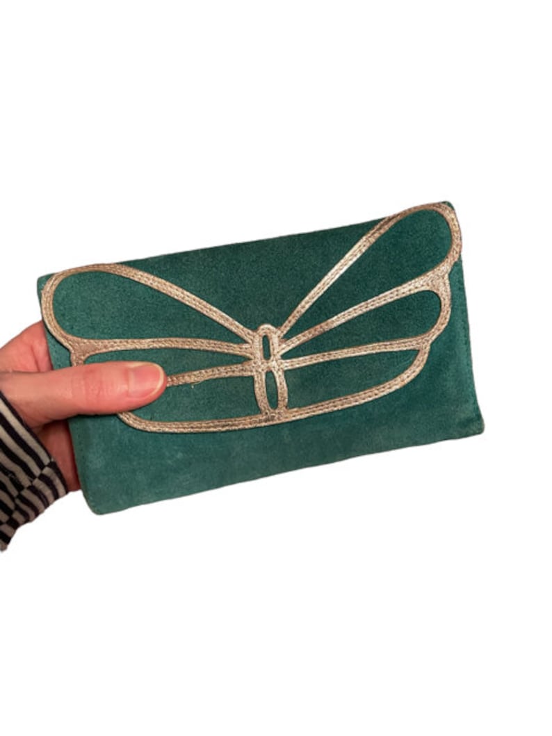 May include: A green suede clutch with a gold butterfly design.