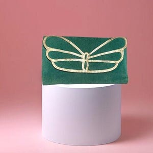May include: A green velvet clutch with a gold butterfly design.