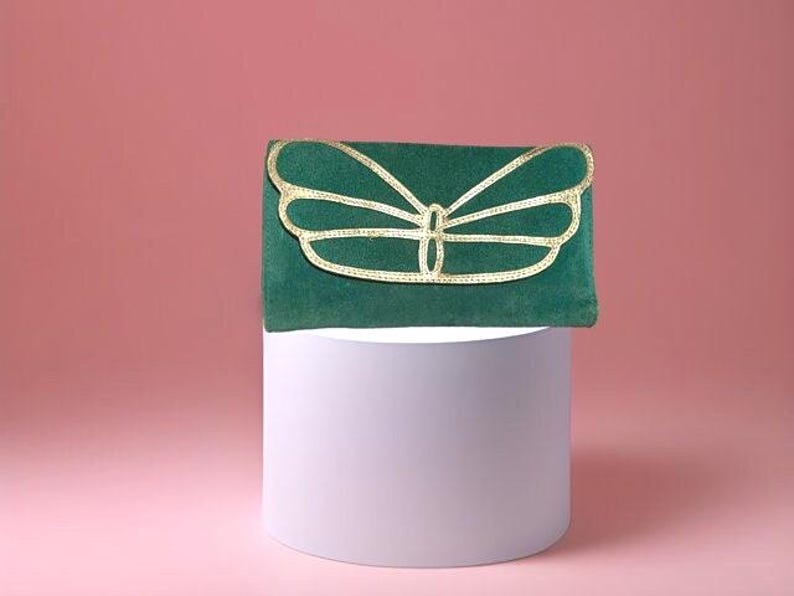 May include: A green velvet clutch with a gold butterfly design.
