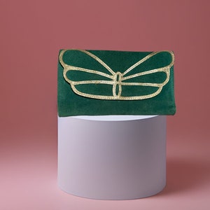 May include: A green velvet clutch with a gold butterfly design.
