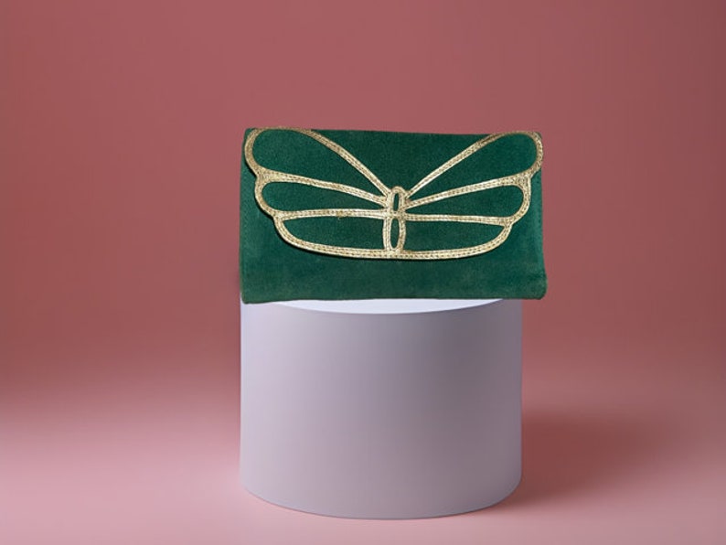 May include: A green velvet clutch with a gold butterfly design.