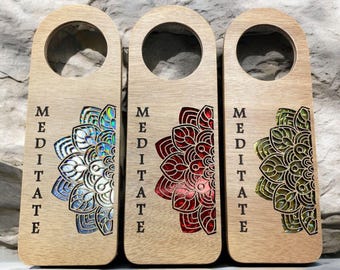 May include: Three wooden door hangers with the word "MEDITATE" engraved on them. Each hanger features a different mandala design in iridescent blue, red, and green.