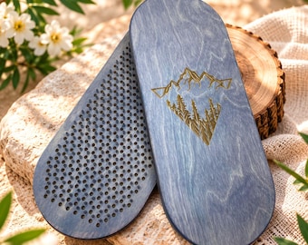 May include: Two oval-shaped wooden boards with a blue-stained finish. One board features a gold-colored engraved mountain and forest graphic. The other board displays a dense grid of small, upright metal nails covering its flat surface.