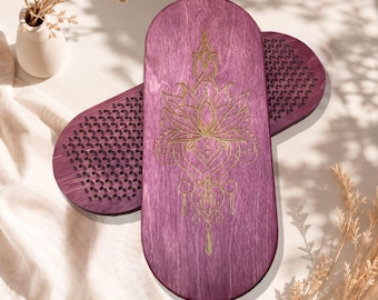 May include: Two oval-shaped purple wooden boards featuring a gold engraved lotus flower design on the front surface. Each board is embedded with a dense grid of sharp metal nails, designed for standing or foot placement, showcasing a wood grain texture.