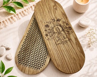 May include: Two oval wooden boards with a light brown grain. One board features a laser-engraved illustration of a person meditating surrounded by planets and sun rays. The other board displays a dense grid of sharp, upright metal nails.