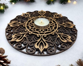 May include: A round wooden candle holder with a detailed, intricate design in shades of brown and gold. The holder features a central space for a tea light candle.