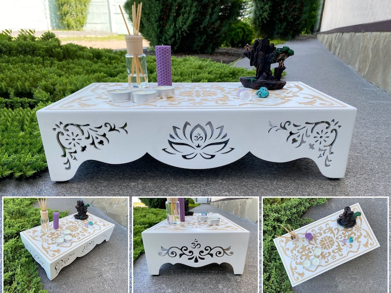 Op de afbeelding: Een witte houten meditatietafel met ingewikkelde uitgesneden ontwerpen en gouden accenten. De tafel heeft een lotusbloem en Om-symbool, met een decoratief patroon op het oppervlak. Het bevat kaarsen, wierook en een diffuser, waardoor een serene sfeer ontstaat.