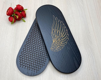 May include: Two black wooden oval-shaped trays. One tray features a gold wing design and the other tray has a pattern of small holes.