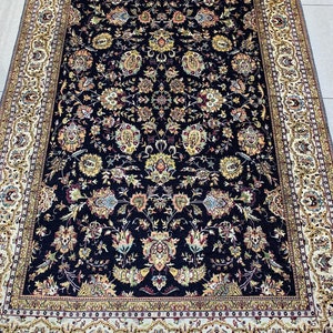 May include: A rectangular, dark blue rug with an intricate floral pattern in shades of yellow, beige, and red. The rug has a detailed border in beige and gold, creating a classic and elegant look. The rug is suitable for living rooms and bedrooms.