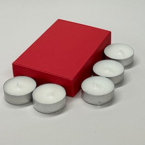 May include: A red box with six white tea light candles. The candles are in a silver holder.